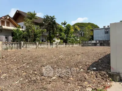 Vacant land plot in a residential area with potential for development, surrounded by greenery and neighboring houses.
