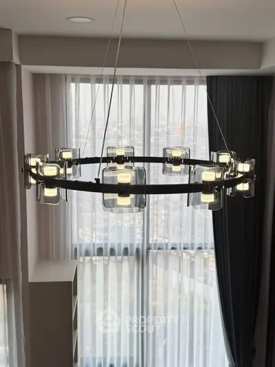 Modern chandelier in a stylish living room with floor-to-ceiling windows and city view.