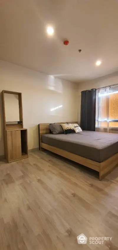 Spacious bedroom with modern wooden bed frame, matching side table, and elegant dark curtains, complemented by warm-toned laminate flooring.