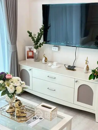Elegant living room with modern decor and wall-mounted TV, featuring stylish furniture and floral arrangements.