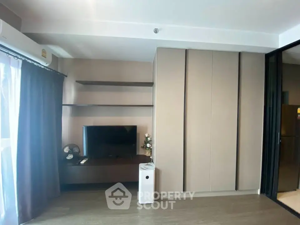 Modern living room with sleek storage and entertainment setup, featuring a TV and air conditioning.