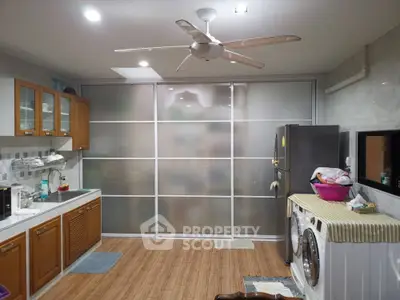 Spacious kitchen with modern appliances and wooden cabinets, featuring a washing machine and large fridge.