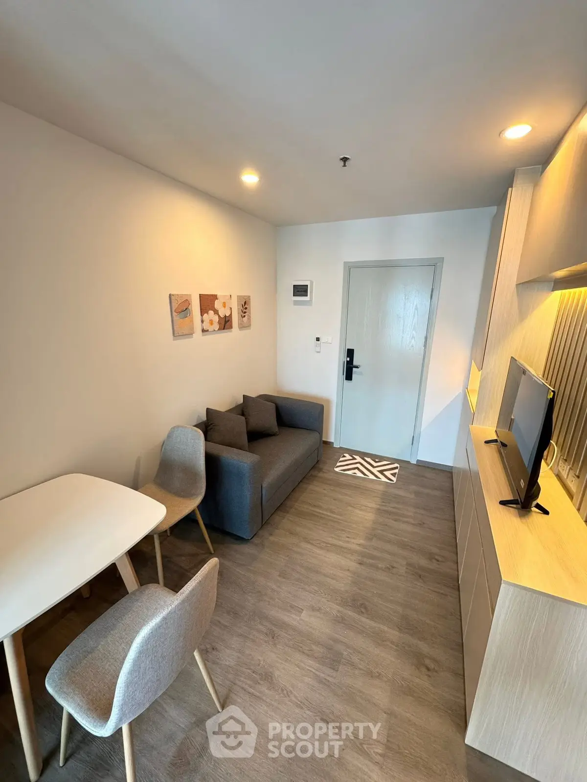 Modern living room with cozy sofa, dining table, and wall-mounted TV in stylish apartment.