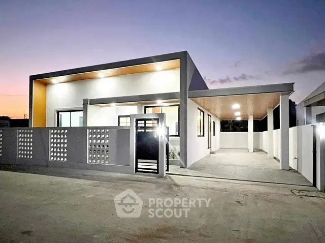 Modern single-story home with sleek design and spacious driveway at dusk.