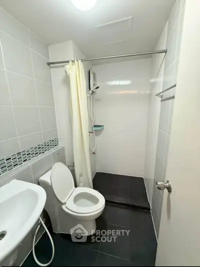 Modern bathroom with sleek design, featuring a shower and toilet in a compact space.