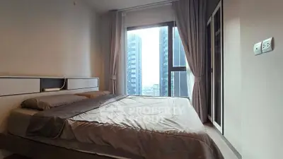 Modern bedroom with large window and city view in high-rise apartment