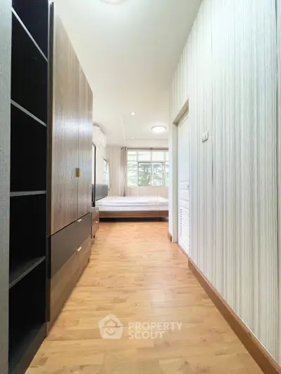 Spacious bedroom with wooden flooring and large window for natural light