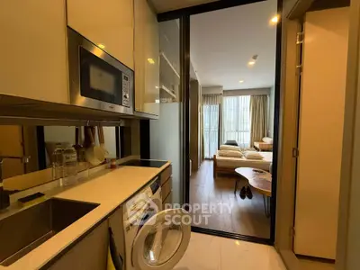 Modern apartment kitchen with washing machine and view into cozy bedroom