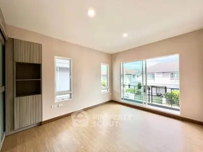 Spacious empty room with large windows and wooden flooring in modern home