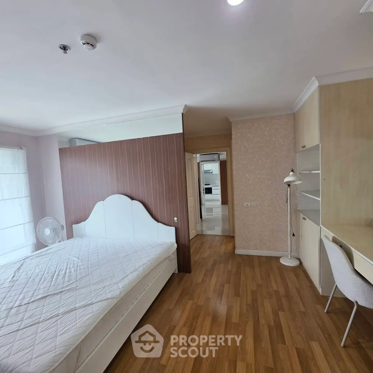 Spacious bedroom with modern decor and wooden flooring in a stylish apartment.