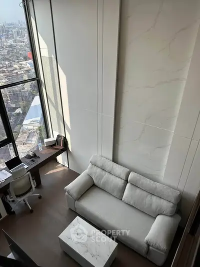 Modern loft-style living room with high ceilings and city view, featuring a cozy sofa and workspace.