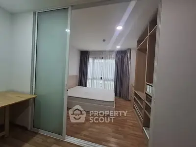Modern bedroom with wooden flooring and sliding glass door in a stylish apartment.