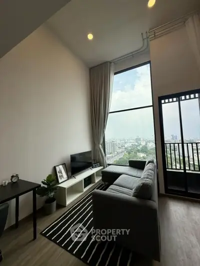 Modern living room with high ceiling and stunning city view from large window and balcony.