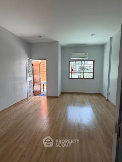 Spacious empty room with wooden flooring and natural light, perfect for customization.