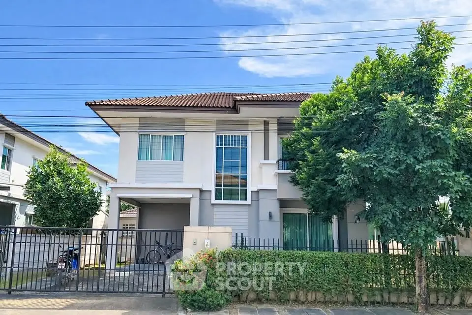 Charming two-story house with lush greenery and modern facade in a serene neighborhood.