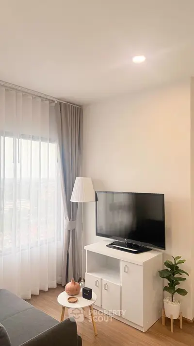 Modern living room with TV, stylish furniture, and large window offering natural light and scenic views.