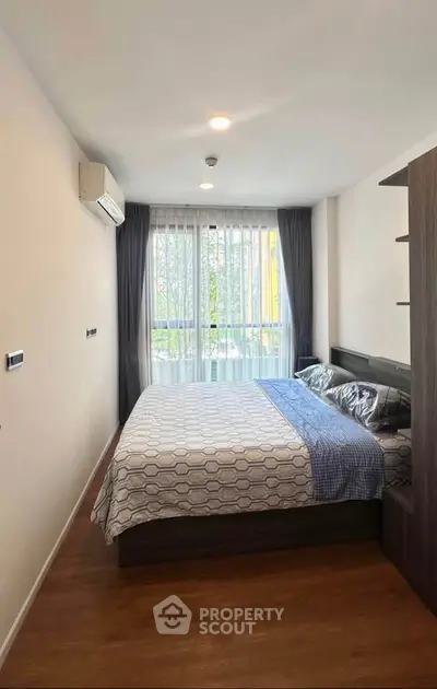 Cozy bedroom with large window and modern decor in a stylish apartment.