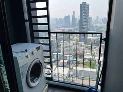 High-rise apartment balcony with washing machine and stunning city skyline view.