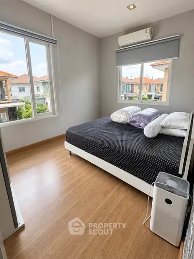 Bright bedroom with large windows and modern air conditioning unit, showcasing a cozy and inviting atmosphere.