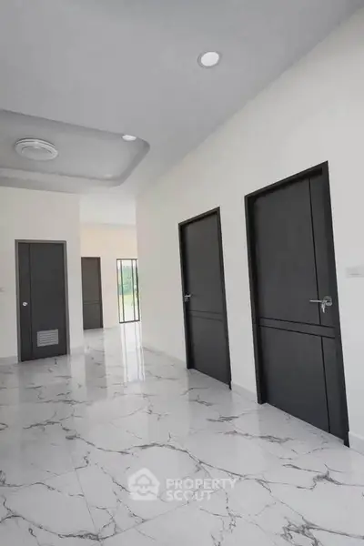 Modern hallway with sleek black doors and marble flooring in a contemporary home.