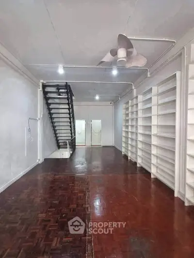 Spacious interior with wooden flooring and built-in shelves, ideal for storage or creative workspace.