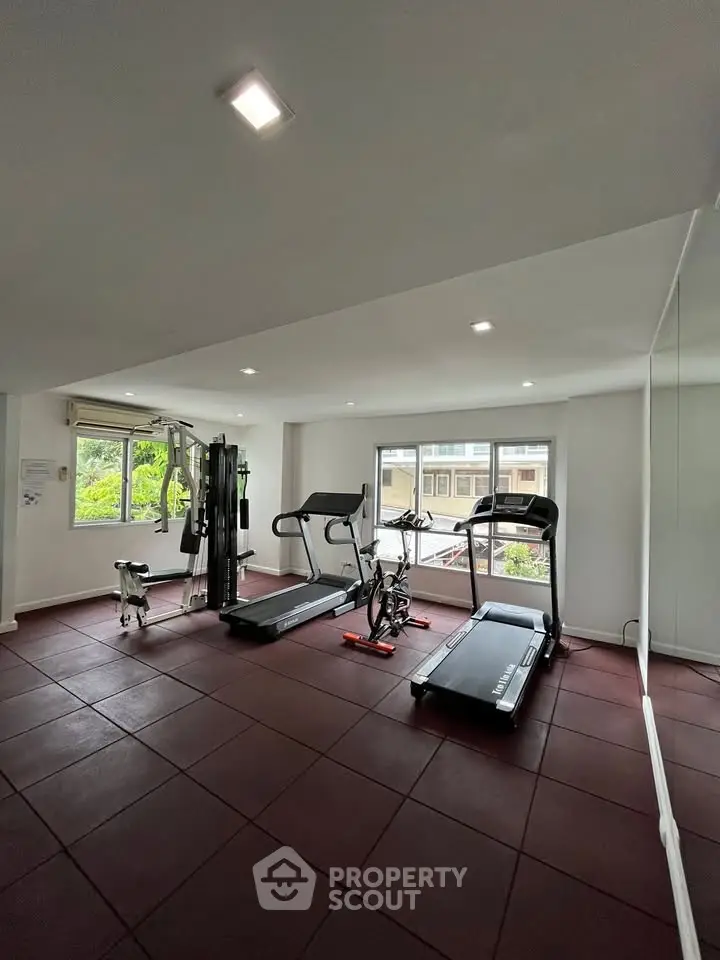 Modern gym with exercise equipment and large windows in a residential building.
