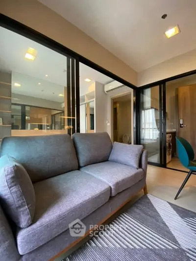 Modern living room with stylish gray sofa and glass partition in contemporary apartment.