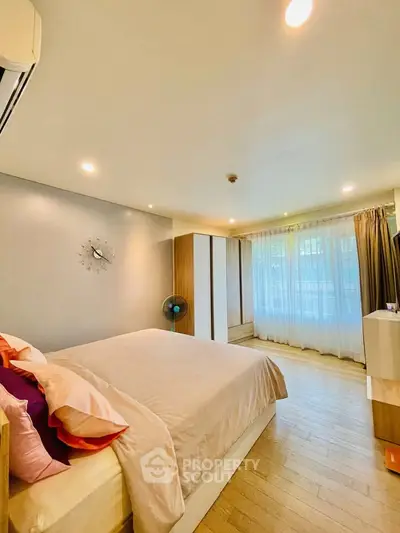 Spacious bedroom with modern decor and large windows for natural light.