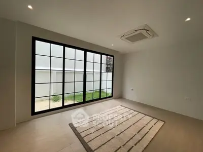 Spacious room with large window and modern ceiling air conditioning unit, perfect for natural light lovers.