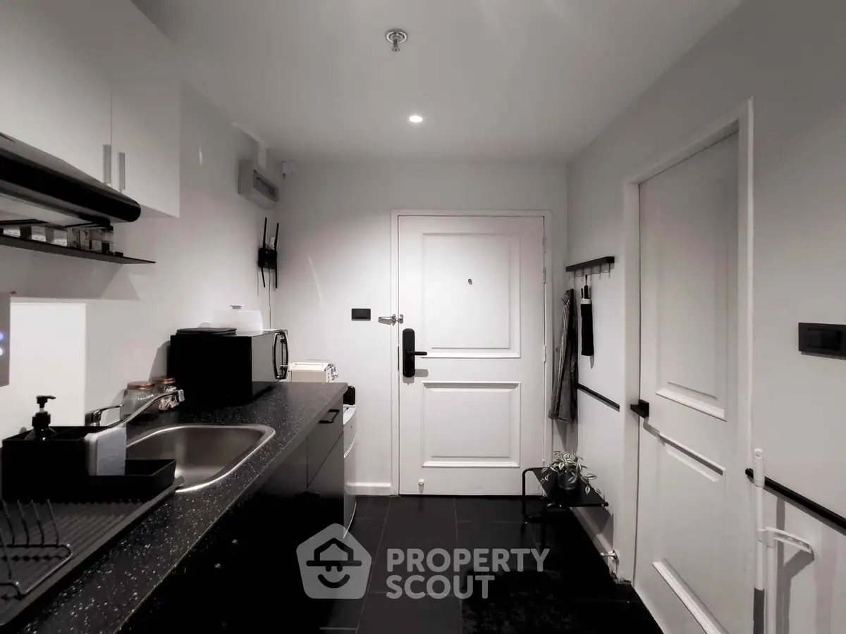 Modern kitchen with sleek black countertops and white cabinetry, featuring a compact layout and stylish design.