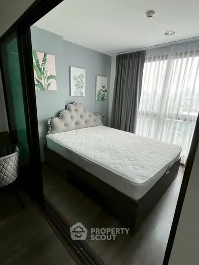 Modern bedroom with stylish decor and large window offering natural light.
