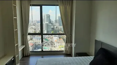 Spacious bedroom with stunning city view from large window in modern apartment.