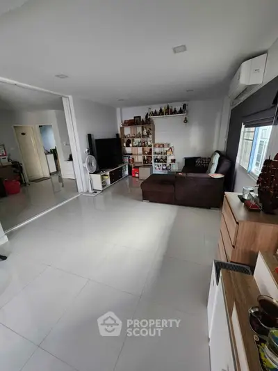 Spacious modern living room with sleek tile flooring and stylish shelving.