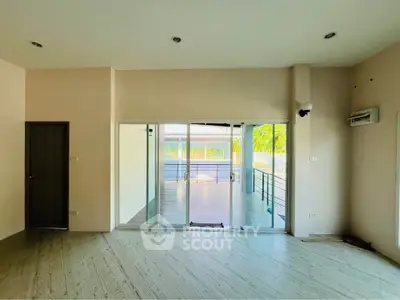 Spacious living room with sliding glass doors leading to a bright balcony, featuring modern flooring and neutral walls.