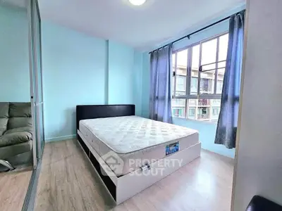 Bright bedroom with large window and modern furnishings in a stylish apartment.