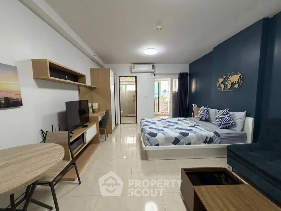 Modern studio apartment with stylish decor and open layout, featuring a cozy bed, TV area, and dining space.