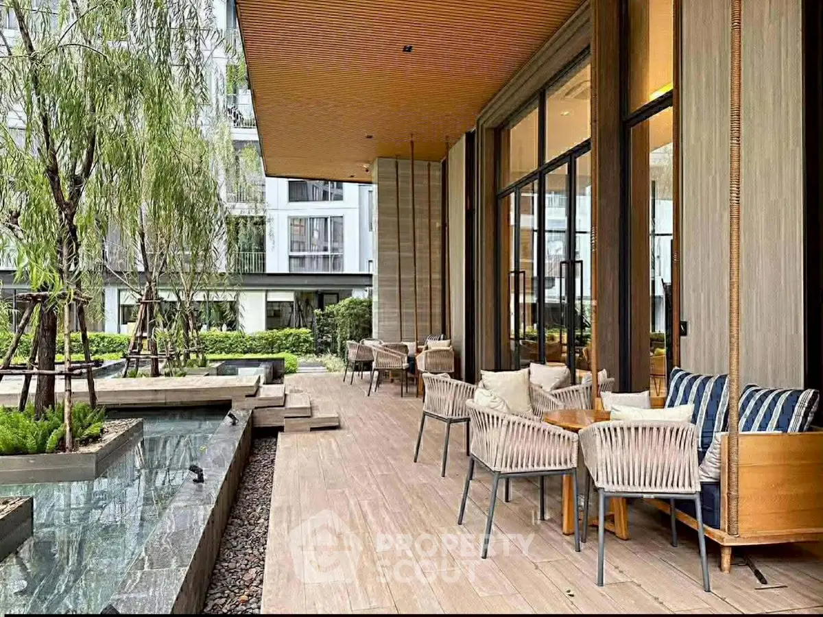 Luxurious outdoor patio with modern seating and serene water feature in upscale residential complex.