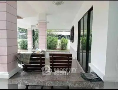 Spacious covered patio with seating area and lush garden view, perfect for outdoor relaxation.