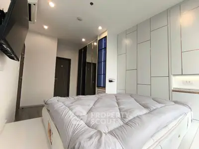 Modern bedroom with sleek design and ample storage space, featuring a cozy bed and built-in wardrobe.