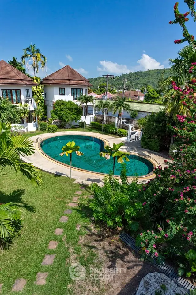 Luxurious villa with heart-shaped pool and lush garden in tropical paradise setting.