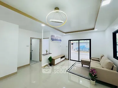 Modern living room with elegant lighting and cozy seating area, featuring large windows for natural light.