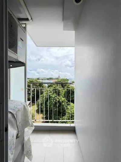 Charming balcony with scenic view of lush greenery and distant water, perfect for relaxation.