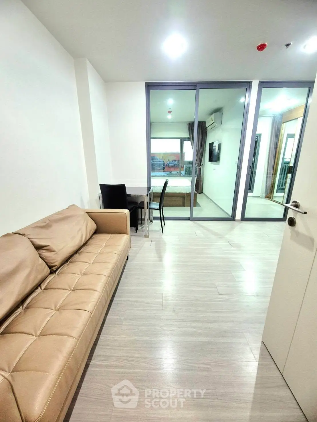 Modern living room with beige sofa and glass doors leading to balcony