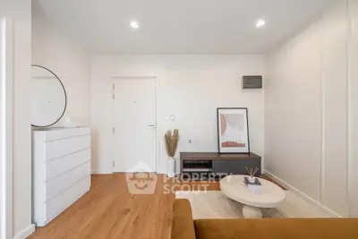 Modern living room with stylish decor and wooden flooring, featuring a round coffee table and wall art.