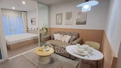 Modern open-plan living room with cozy sofa and dining area, adjacent to a stylish bedroom.