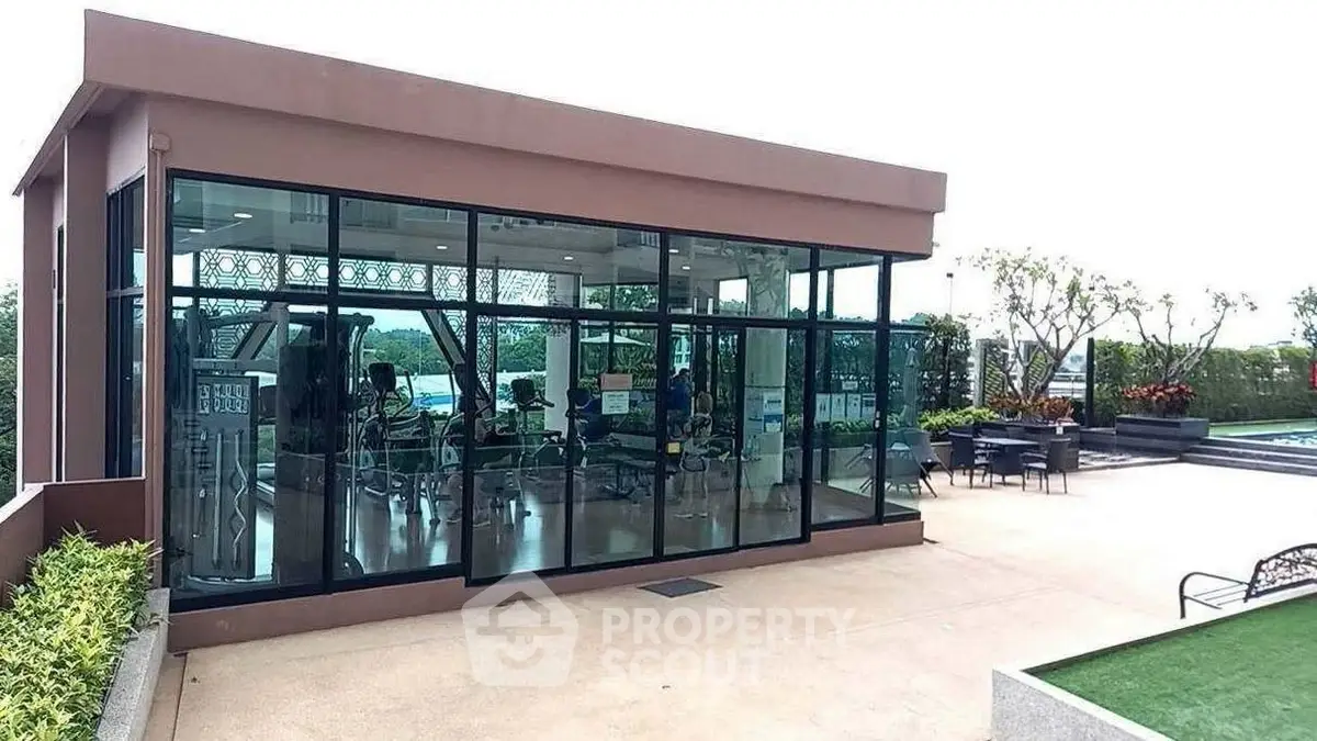 Modern gym with glass walls and outdoor seating in a luxury residential complex