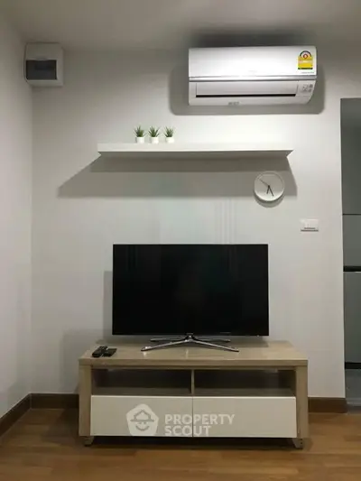 Modern living room with sleek TV stand, wall-mounted shelf, and air conditioning unit.
