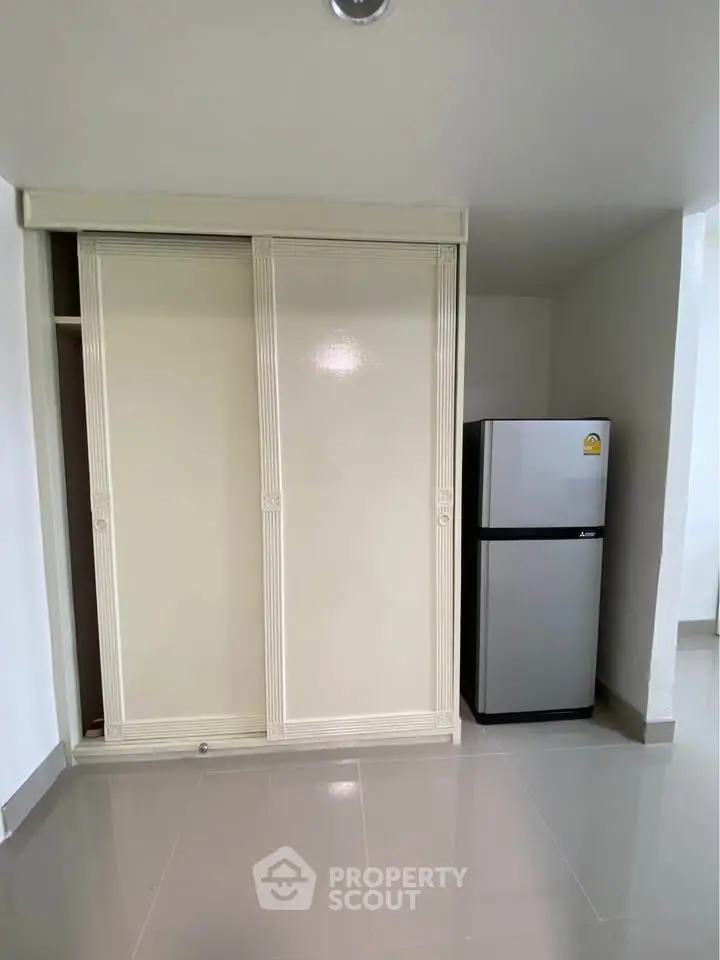 Modern interior with sleek fridge and sliding closet doors in a minimalist space.
