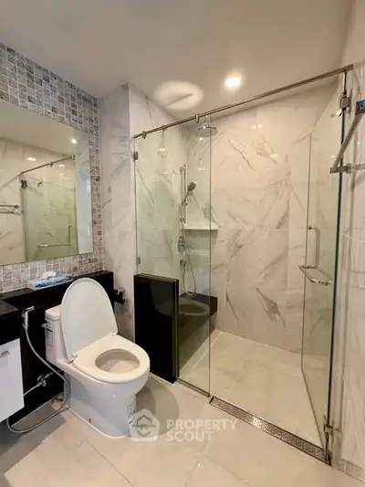 Modern bathroom with glass shower and sleek fixtures in luxury apartment.