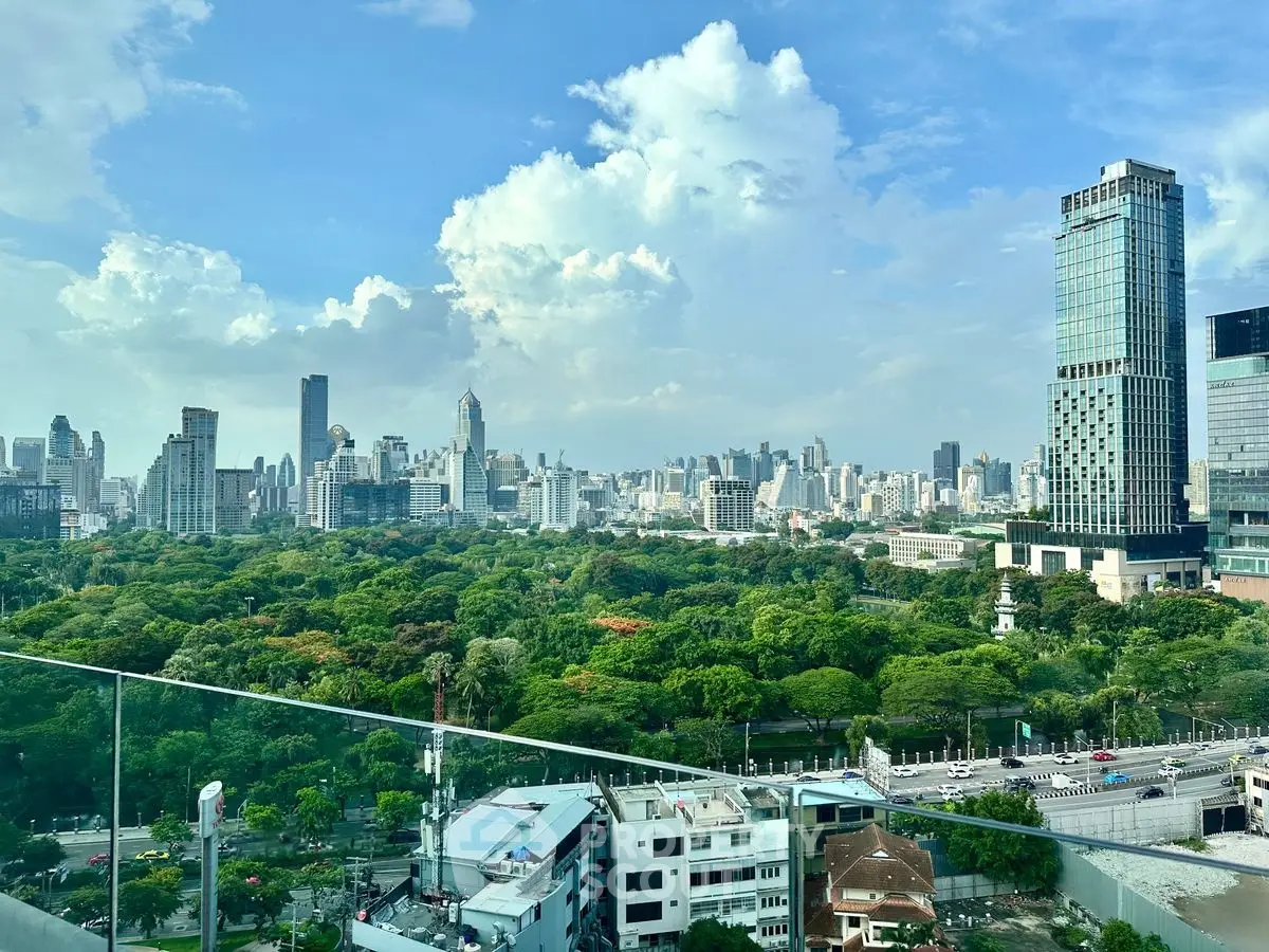 Stunning cityscape view from a high-rise balcony overlooking lush green park and skyline.